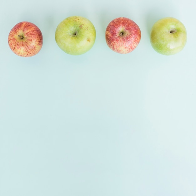 Photo gratuite rangée de pommes sur bleu