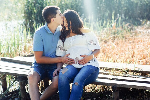 Les rayons du matin éclairent le couple charmant assis sur le banc de la rivière