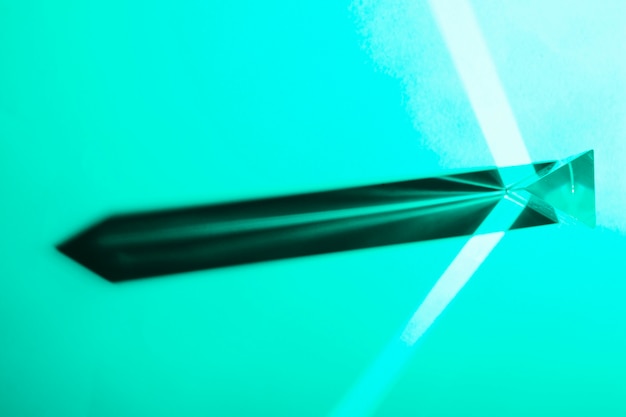 Photo gratuite rayons sortant du prisme de cristal sur fond turquoise
