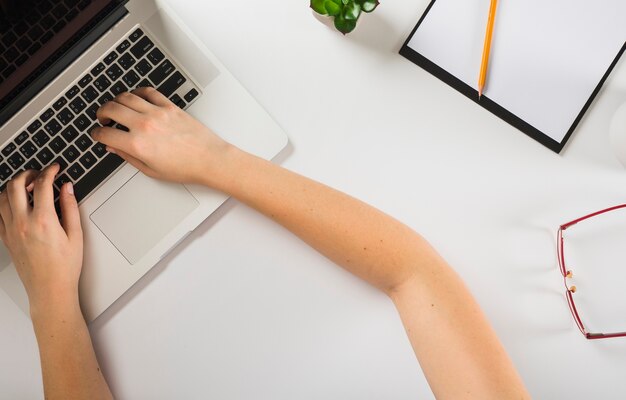 Recadrer les mains à l&#39;aide d&#39;un ordinateur portable sur le bureau