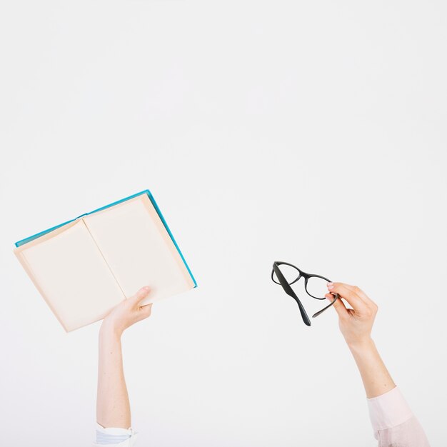 Recadrer les mains avec un livre et des lunettes