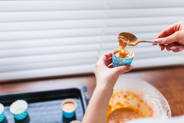 Recadrer les mains en remplissant la tasse avec la pâte