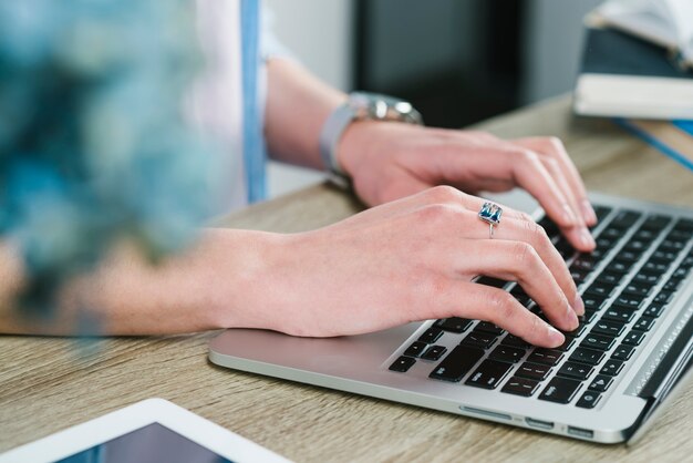 Recadrer les mains en utilisant un ordinateur portable dans le bureau