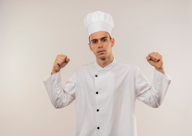 À la recherche de jeunes hommes caamera cuisinier portant l'uniforme de chef faisant un geste fort sur un mur blanc isolé avec copie espace