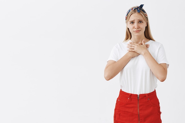Photo gratuit reconnaissant et touché jeune fille blonde posant contre le mur blanc