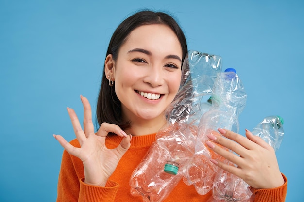 Photo gratuite le recyclage est formidable une jeune femme souriante tenant des bouteilles montre un signe correct approuve un mode de vie éco-vert