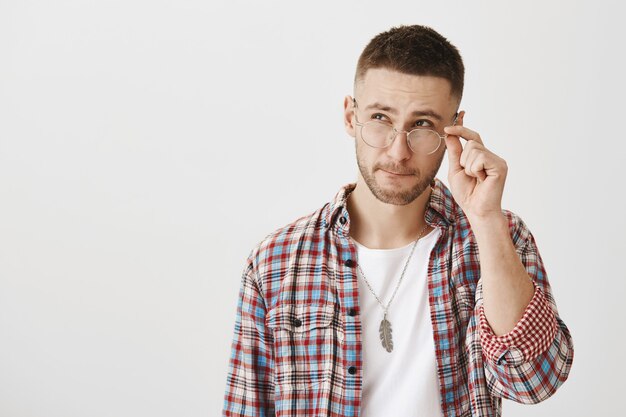 Réfléchi jeune homme avec des lunettes posant