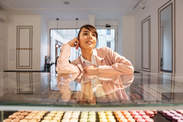 Réfléchi jeune jeune femme choisissant des pâtisseries