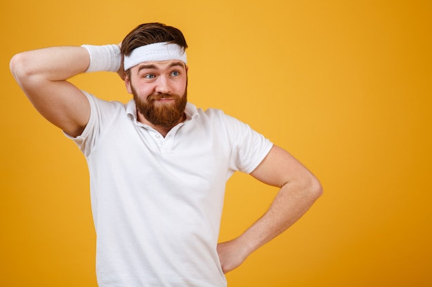 Réfléchi sportif barbu se grattant la tête