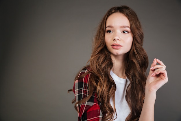 Réfléchie belle jeune femme en chemise à carreaux debout et pensant