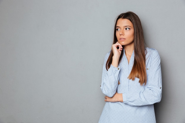 Réfléchie femme brune en chemise à l'écart