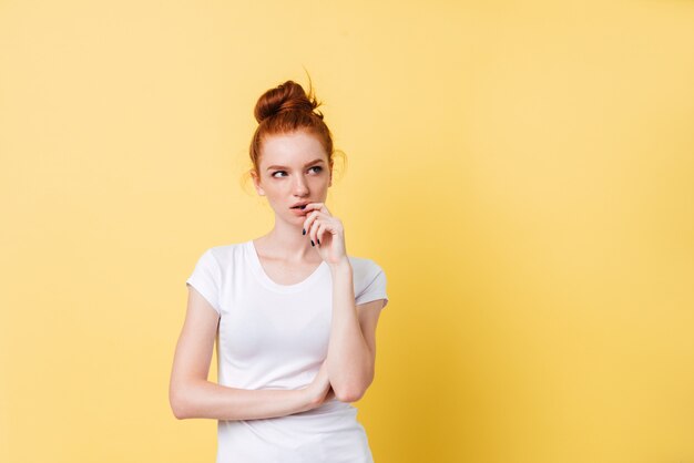 Réfléchie femme gingembre en t-shirt en détournant les yeux