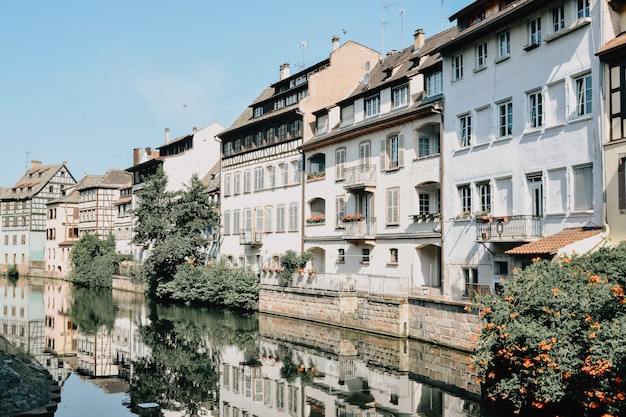 Reflet de maisons blanches aux toits bruns entourés de plantes vertes dans l'eau