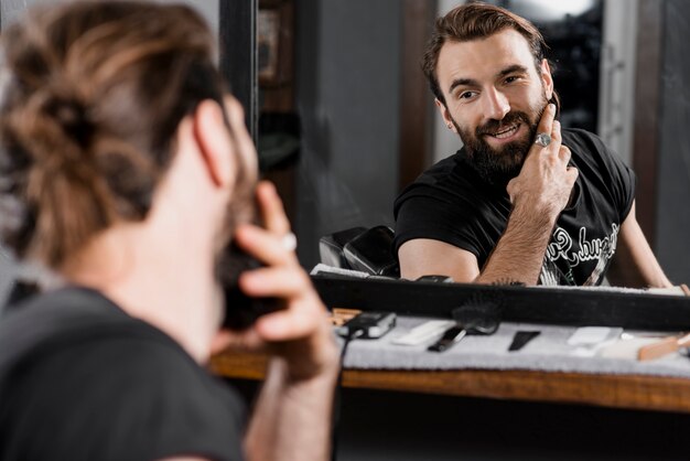 Réflexion d&#39;un client masculin toilettant sa barbe dans un miroir