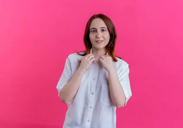 Regardant la caméra jeune fille rousse a attrapé le collier isolé sur fond rose