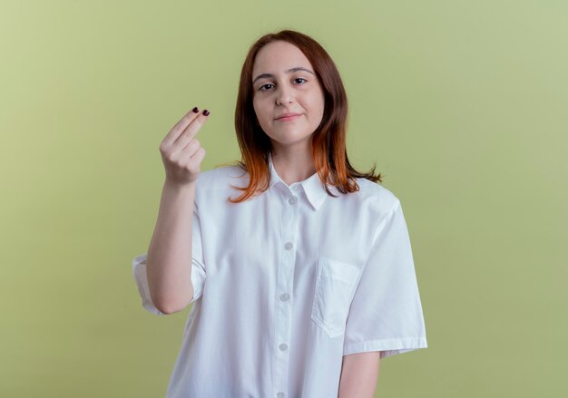 Regardant la caméra jeune fille rousse montrant le geste de pointe isolé sur fond vert olive