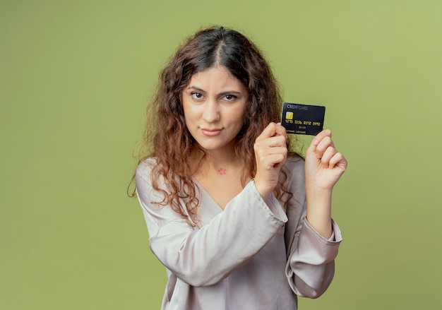 regardant la caméra jeune jolie femme employé de bureau tenant une carte de crédit autour du visage