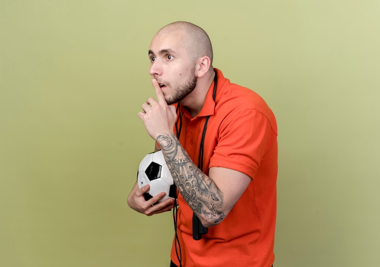 Photo gratuit regardant à côté concerné jeune homme sportif tenant le ballon et montrant le geste de silence