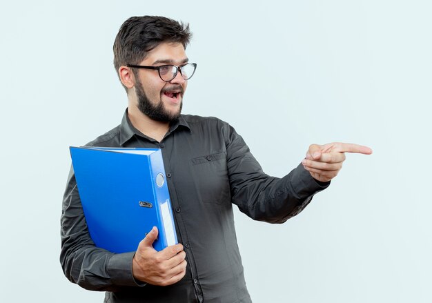 regardant côté heureux jeune homme d'affaires portant des lunettes tenant le dossier et les points sur le côté