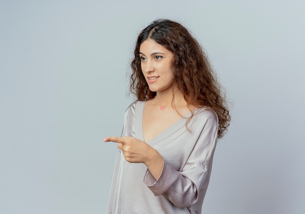 Regardant à côté heureux jeune jolie femme employé de bureau points à côté isolé sur fond blanc avec copie espace