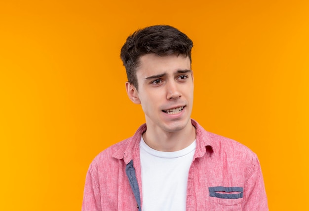 Photo gratuite regardant à côté de la pensée caucasien jeune homme portant une chemise rose sur un mur orange isolé