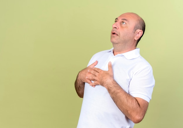 Regardant l'homme mûr surpris mettant les mains ensemble sur la poitrine