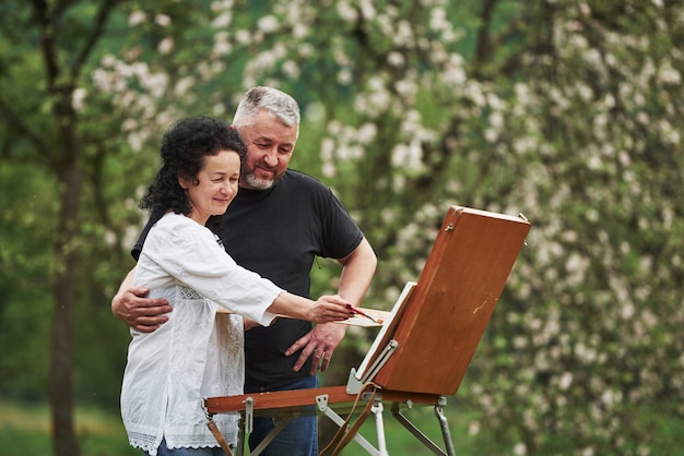 Regarde ça. Couple d'âge mûr ont des journées de loisirs et travaillent ensemble sur la peinture dans le parc