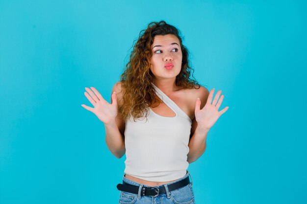 Regarder à droite fille lève les mains sur fond bleu