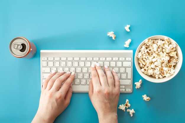 Photo gratuite regarder des films avec du pop-corn sur fond bleu à plat