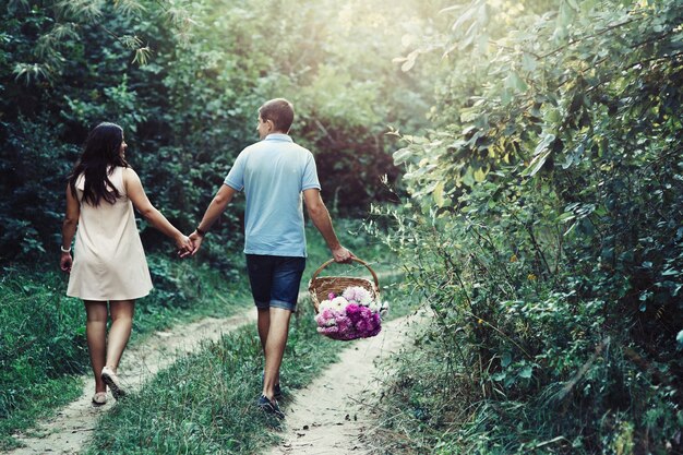 Regarder par derrière à un couple charmant en se tenant par la main tout en marchant le long du chemin