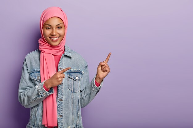 Regardez de cette façon. Heureuse belle femme arabe qui pointe à droite