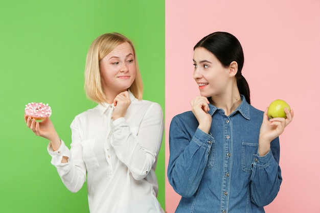 Photo gratuite régime. concept de régime. nourriture saine. belles jeunes femmes choisissant entre les fruits et le gâteau impitoyable