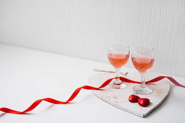 Réglage de la table de fête de la saint-valentin avec deux verres de bonbons au chocolat en forme de coeur rouge vin rose
