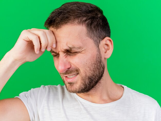 Regretté jeune homme malade mettant la main sur le front isolé sur vert