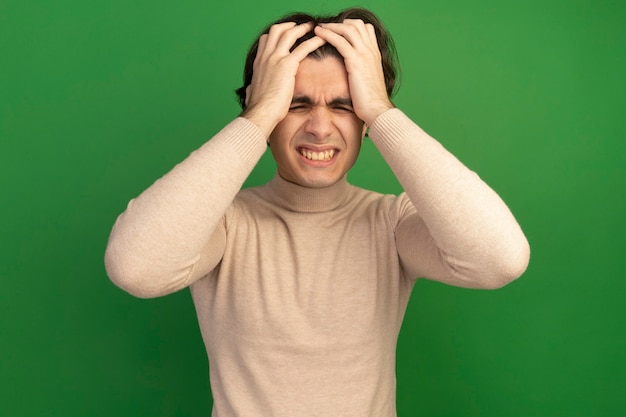 Regretté les yeux fermés jeune beau mec a attrapé la tête isolée sur le mur vert