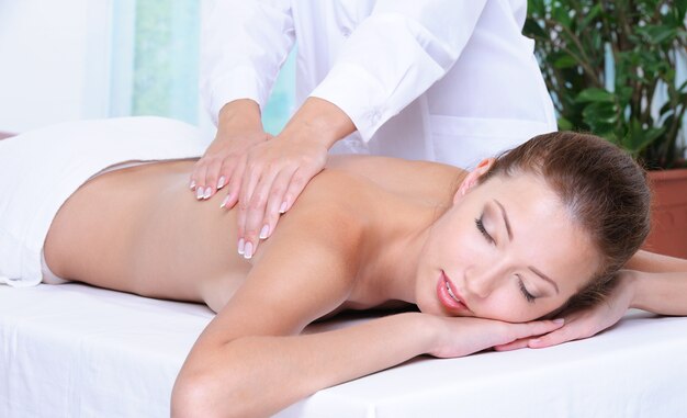 Relaxation et massage du dos pour la belle jolie fille dans un salon de beauté