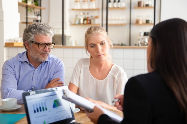 Rencontre d'agent d'assurance financière avec des clients jeunes et matures lors d'un co-working, montrant son accord et expliquant les détails