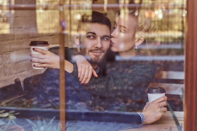 Photo gratuite rendez-vous romantique, couple amoureux. belle fille assise sur les genoux de son petit ami sur le café derrière la fenêtre.