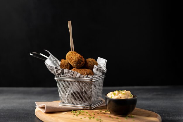 Repas contenant des croquettes et de la mayonnaise sur une assiette en bois