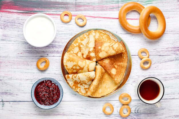 Repas du festival de Maslenitsa. Blini de crêpes russes à la confiture de framboises, miel, crème fraîche et caviar rouge, morceaux de sucre, fromage cottage, bubliks sur fond clair