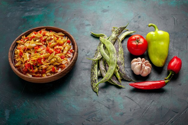 Repas de légumes en tranches demi-vue avec différents ingrédients et légumes frais sur une surface bleu foncé