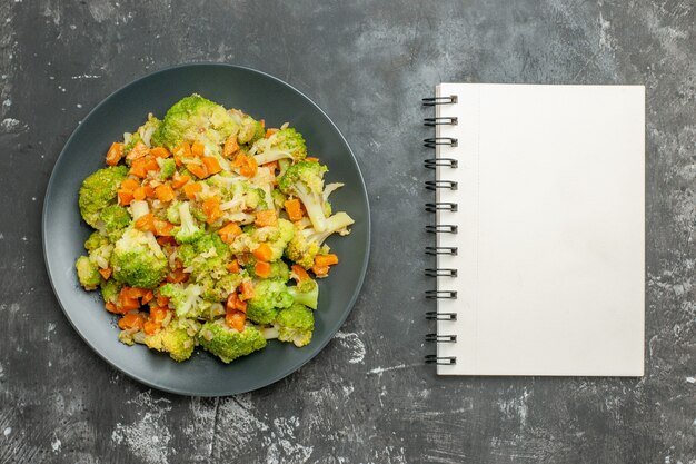 Repas sain avec du brocoli et des carottes à côté de l'ordinateur portable sur le tableau gris