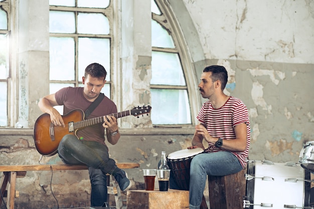 Photo gratuite répétition du groupe de musique rock. joueur de guitare électrique et batteur derrière la batterie.