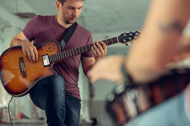 Photo gratuite répétition du groupe de musique rock. joueur de guitare électrique et batteur derrière la batterie.