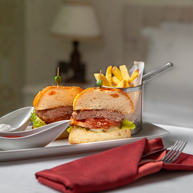 Restauration rapide dans un plateau de service avec hamburger, frites vue latérale sur un fond de chambre