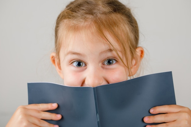 Retour au gros plan de concept d'école. petite fille tenant un cahier ouvert.