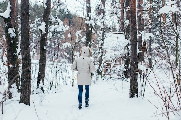 Retour de l'homme en manteau d'hiver à pied dans la forêt de neige