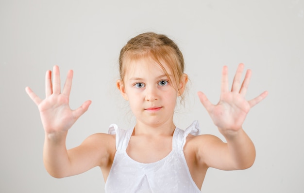 Retour à la vue latérale du concept de l'école. petite fille montrant ses paumes.