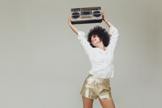Photo gratuite rétro émotionnelle femme habillée en chemise tenant boombox.