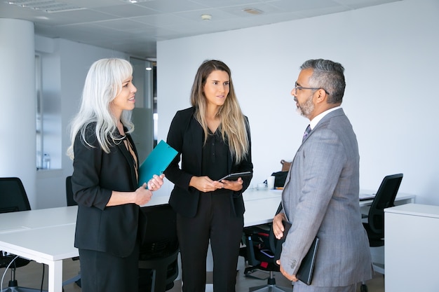 Réunion de partenaires commerciaux confiants positifs et discussion de collaboration, dossier de détention et tablettes. Vue de côté. Concept de communication ou de partenariat